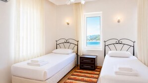 A bedroom with two single beds, a nightstand, a window with a view, and a ceiling fan.