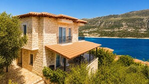 A stone house with a balcony overlooking a coastal area.