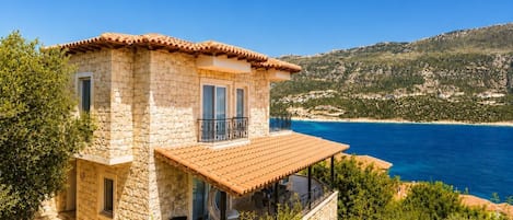 Una casa de piedra con balcón que da a la costa.