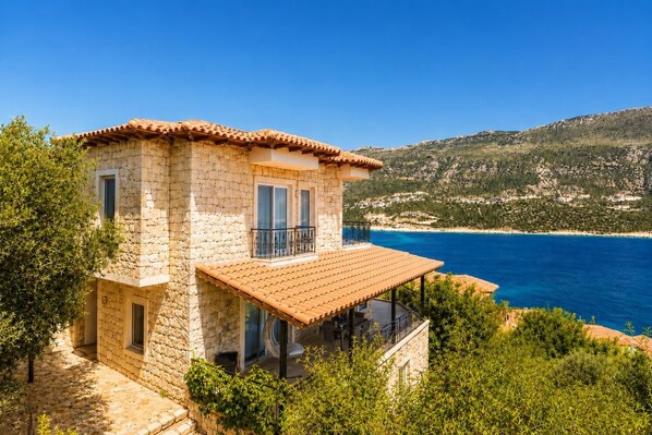 A stone house with a balcony overlooking a coastal area.