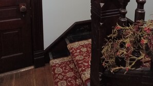 A wooden staircase with a handrail, a window with stained glass, and a door with a brass handle.