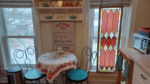A cozy kitchen with a round table, teal chairs, and a 'Kitchen Rules' sign.