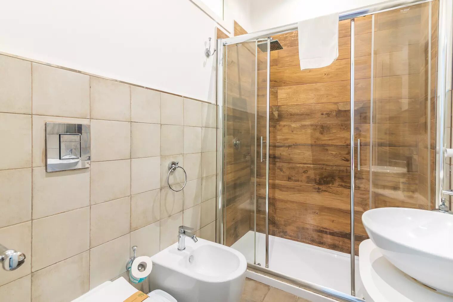 A modern bathroom with a glass shower enclosure, a sink, and a bidet.