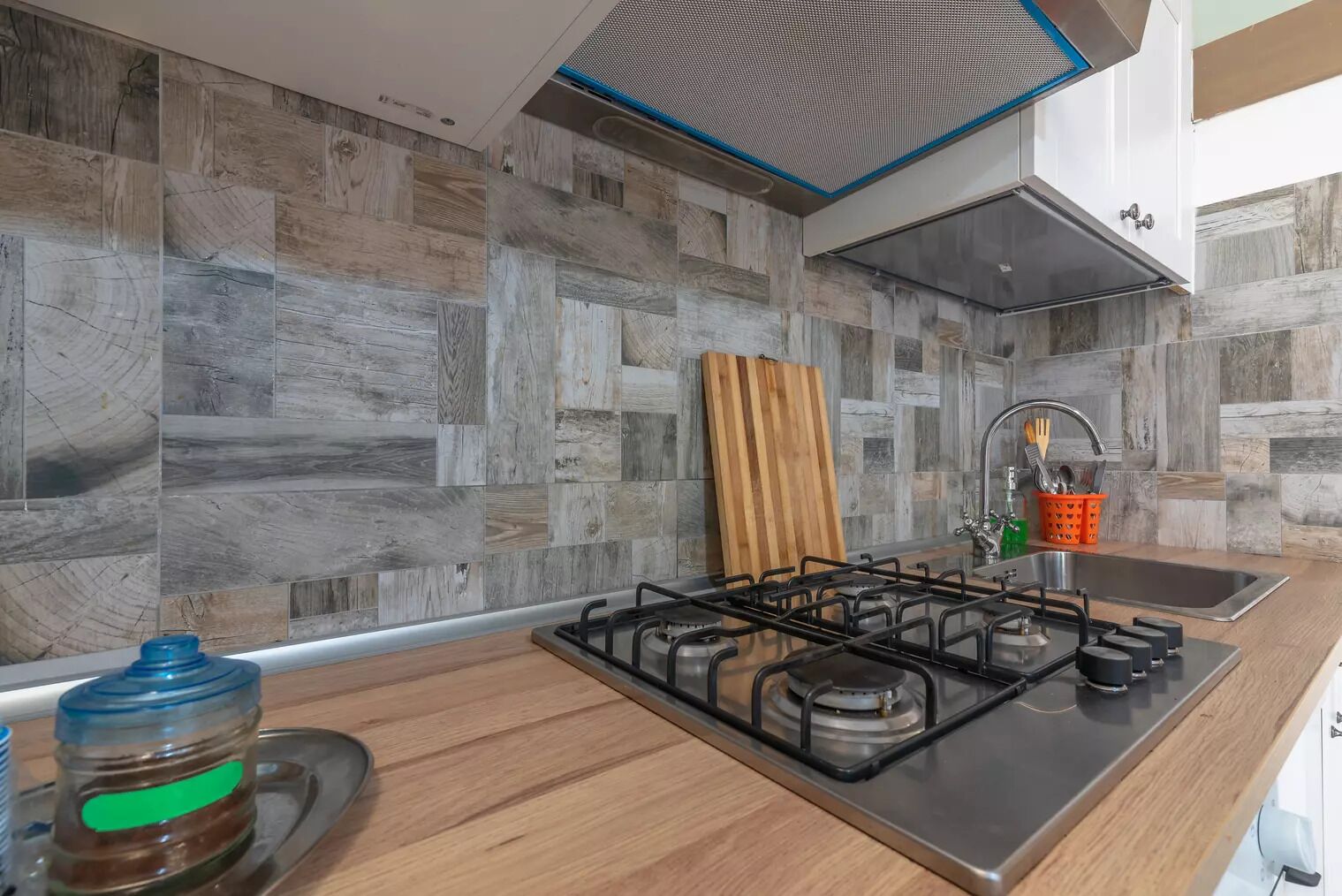 Una cocina moderna con estufa a gas, encimera de madera y salpicadero con diseño que imita la madera.