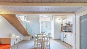 Una cocina moderna con armarios blancos, una estufa a gas y un comedor con una mesa y sillas.