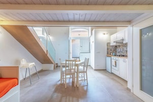 A modern kitchen with white cabinets, a gas stove, and a dining area with a table and chairs.