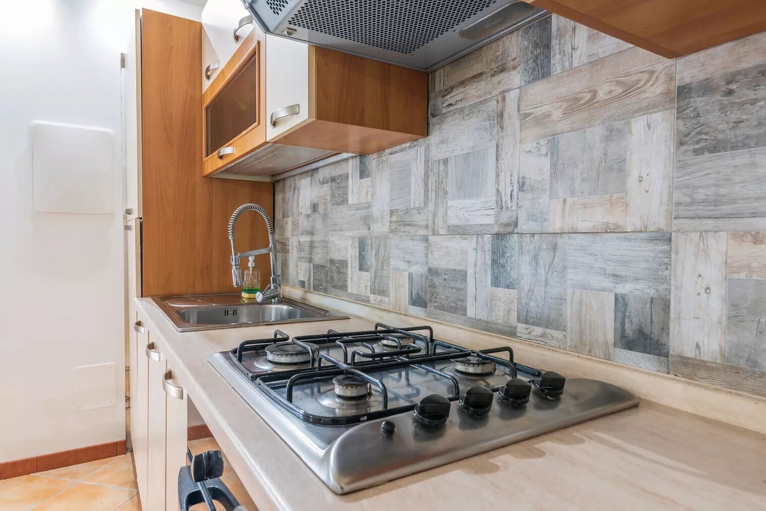 A kitchen with a gas stove, wooden cabinets, and a tiled backsplash.
