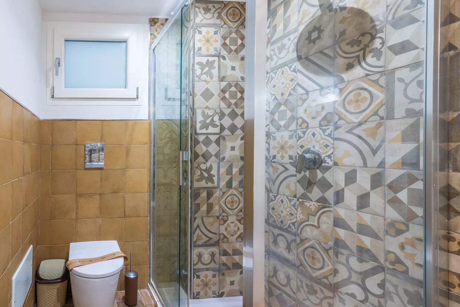 A bathroom with a shower, toilet, and a window.