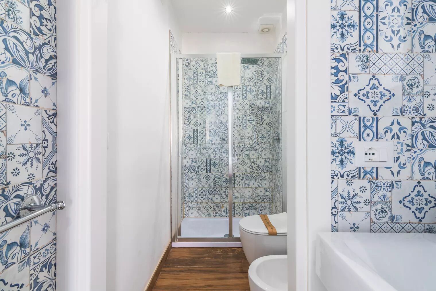 Un bagno con doccia, WC e vasca, tutti rivestiti con decorazioni blu e bianche.