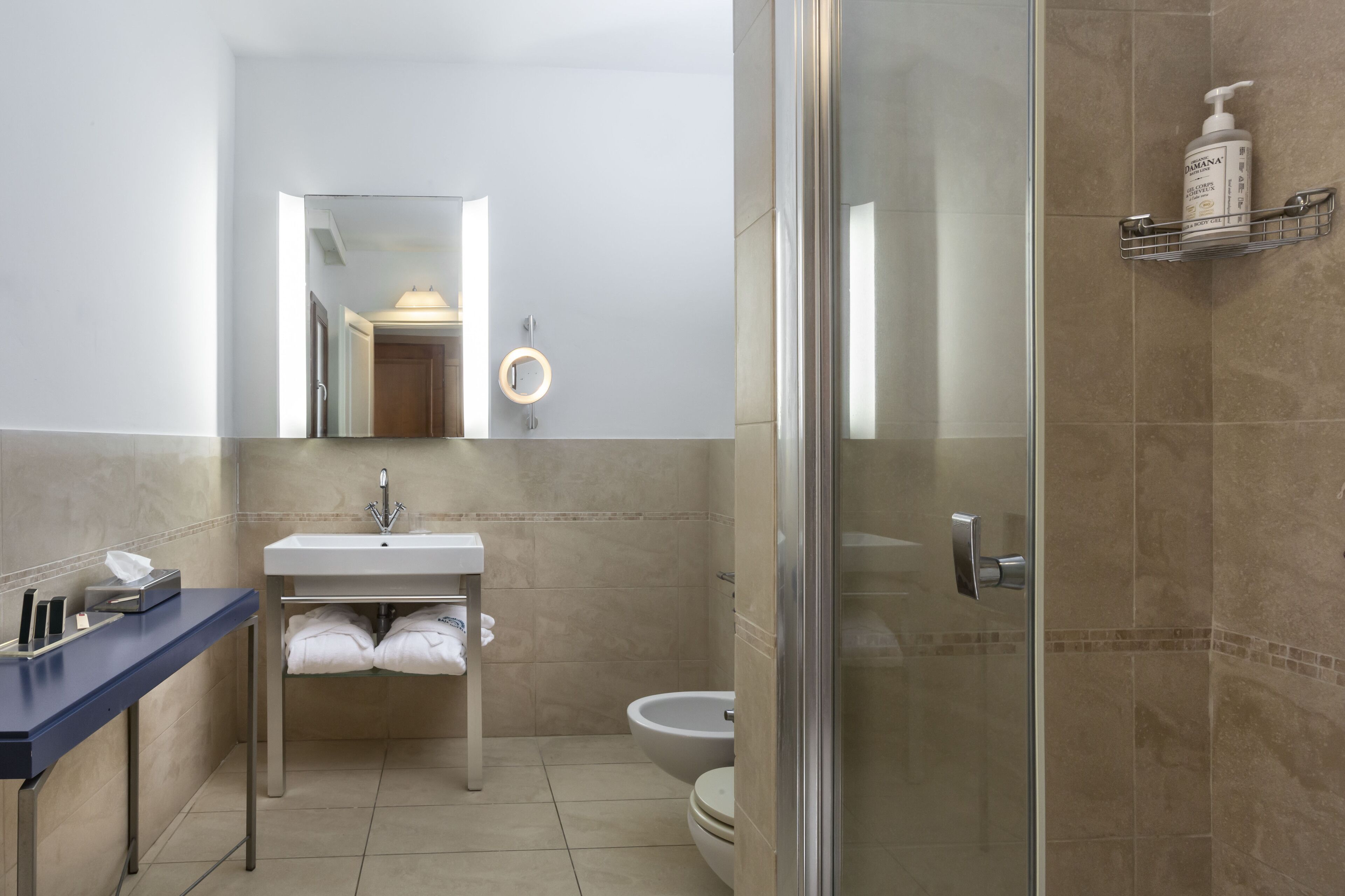 A modern bathroom with a sink, mirror, toilet, and shower area.