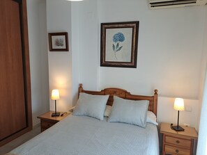 A neatly arranged bedroom with a wooden bed, two bedside tables with lamps, and framed artwork on the walls.