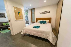 A bedroom with a bed, a bench, and a door leading to a balcony.
