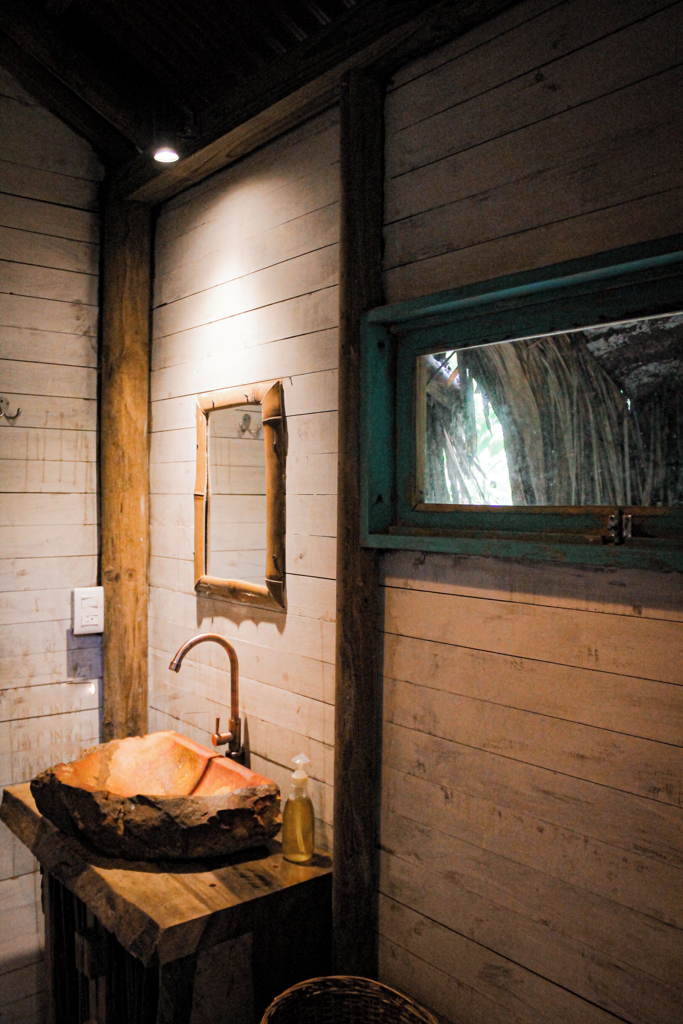 A rustic bathroom with a wooden sink, a mirror, and a window.