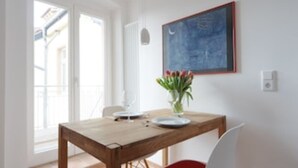 A dining area with a wooden table, a vase with flowers, and a framed picture on the wall. - Second home Heidelberg | Holiday apartment for short or long term (Heidelberg)