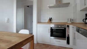 A kitchen with white cabinets, a wooden countertop, a stainless steel oven, and a coffee maker. - Second home Heidelberg | Holiday apartment for short or long term (Heidelberg)
