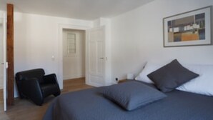 A bedroom with a bed, a chair, and a door leading to another room. - Second home Heidelberg | Holiday apartment for short or long term (Heidelberg)