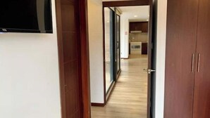 A hallway with wooden doors and a view into a kitchen area. - Beautiful Suite in Cuenca (Cuenca)