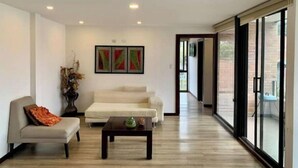 A spacious living room with a sofa, a coffee table, and a painting on the wall.