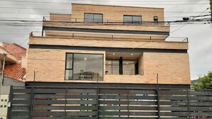 A modern two-story house with a brick facade, large windows, and a black metal fence.