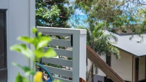 A white balcony railing with a wooden handrail, overlooking a residential area with houses and trees. - Seascape Whitsundays (Airlie Beach)
