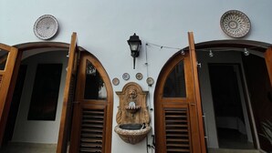 A building with two arched windows, a decorative wall-mounted light fixture, and two doorways with wooden shutters. - OLD MOON OLD SAN JUAN (San Juan)