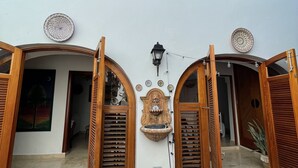 A two-story building with arched wooden doors and windows, a decorative wall-mounted light fixture, and a small wall-mounted shelf with a plant. - OLD MOON OLD SAN JUAN (San Juan)