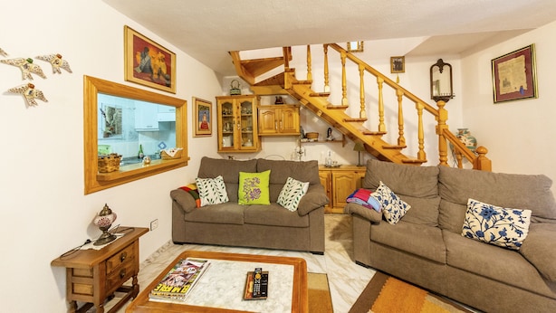 A living room with a wooden staircase, two sofas, a coffee table, and a dining table. - enjoy the nature (NOCEDO DE CURUEÑO)