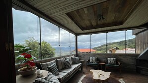 A spacious room with a large window, a wooden ceiling, a sofa, a coffee table, and a view of the landscape.