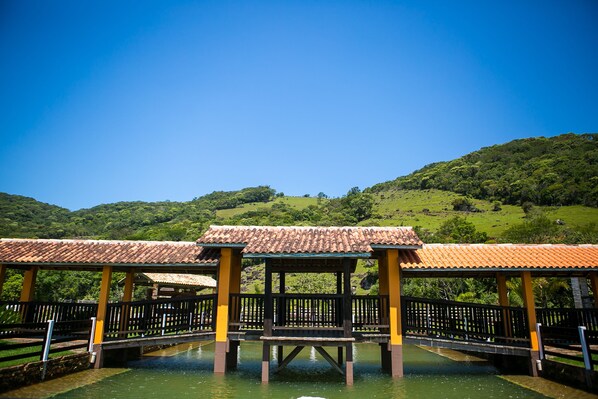 A traditional pavilion with a tiled roof, surrounded by water, set against a backdrop of lush green hills. - Eco Mirante Hotel by RB Hotelaria (Paulo Lopes)