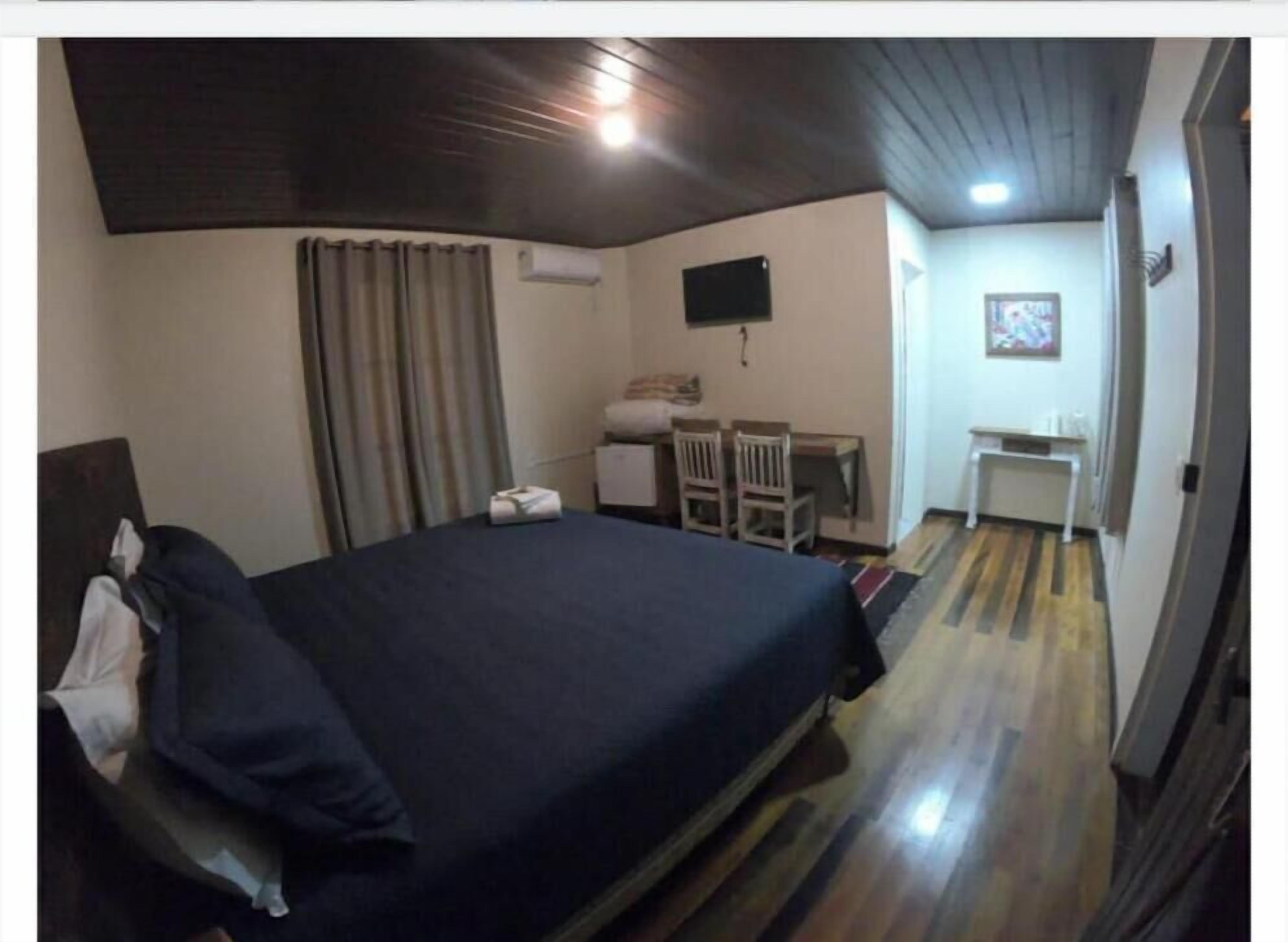 Une chambre à coucher comprenant un lit, un bureau, une chaise, un téléviseur et une petite table.