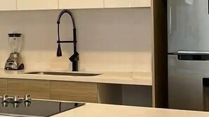 A modern kitchen with a central island, stainless steel appliances, and light wood cabinetry. - Condominios DTR (Puerto Vallarta)