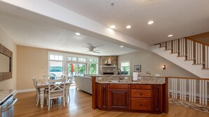 A spacious kitchen with a large island, wooden cabinets, and a stone fireplace.