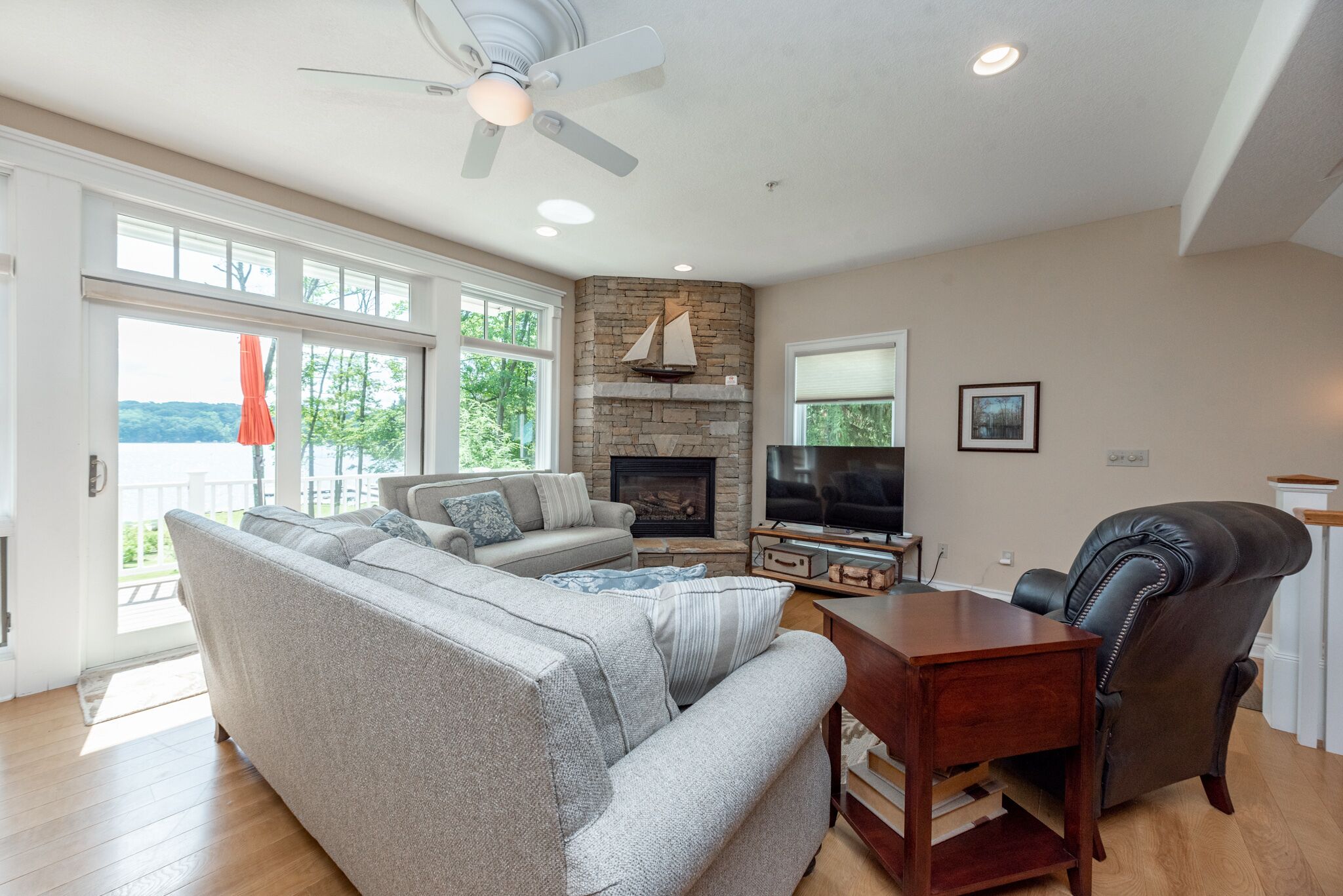 A spacious living room with a fireplace, a large sofa, a television, and a leather chair.