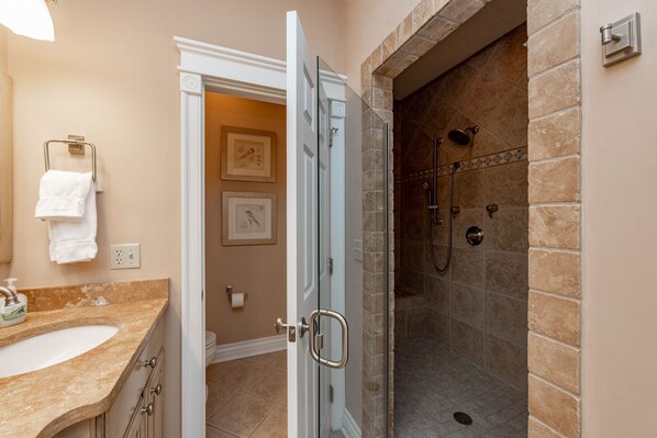 Ein Badezimmer mit Waschbecken, Duschabtrennung aus Glas und Dusche mit Steinwand.