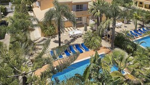 Ett semesterparadis med en swimmingpool omgiven av palmer och solstolar.