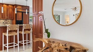 Eine moderne Küche mit Holzschränken, Pendelleuchten und einer Bar mit gewobenen Hocker.