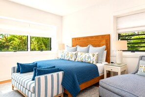 Une chambre à coucher comprenant un lit, une table de chevet, une chaise et une fenêtre donnant sur un paysage verdoyant.