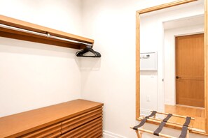 Quarto com um banco de madeira, um espelho e um varal.
