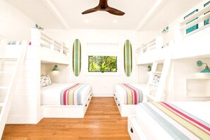 Quarto com beliches, janela com vista para o verde e ventilador de teto.
