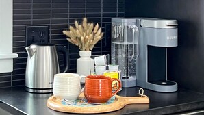 Een keuken met donkere kastjes, een koffiezetapparaat, een waterkoker en een snijplank met een mes.
