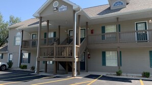 Un motel à étages, doté d’un porche avant couvert, d’un escalier menant à l’étage supérieur et d’un parking avec des places délimitées.