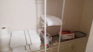 Une petite salle de bain avec des toilettes, une étagère avec des serviettes et une boîte de papier toilette.