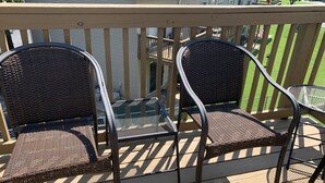 Une terrasse en bois avec deux fauteuils en osier et une table en métal.