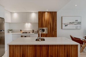 Enjoy meals in the kitchen with a central island, stainless steel sink, and microwave, adjacent to a dining area with a glass table and comfortable seating.