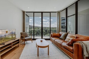 Relax in this stylish living room with a panoramic view of the city and lush greenery.
