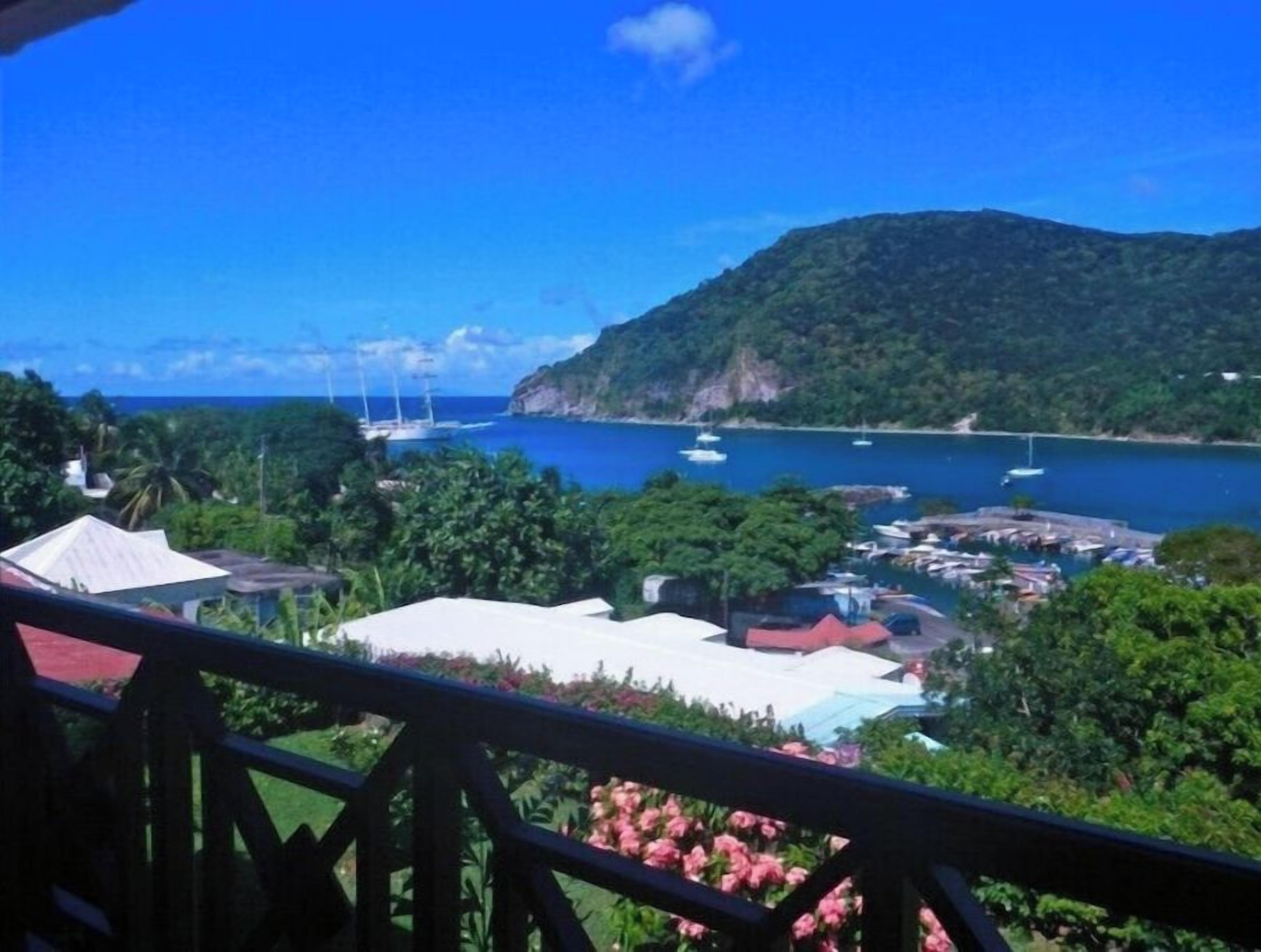 Une vue sur la côte, avec des bateaux, une montagne et un port de plaisance.