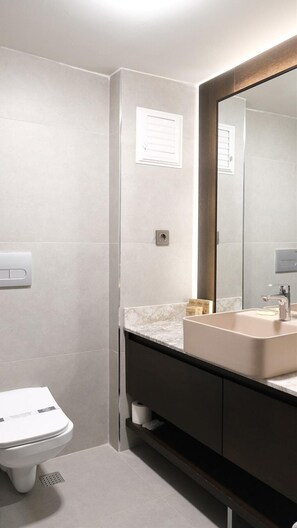 Un baño moderno con inodoro, lavamanos y espejo.