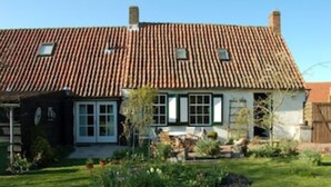 A traditional house with a tiled roof, a front garden, and a visible chimney. - Cozy farmhouse, Zeeland, original, large garden, wallbox 22KW (Gapinge)