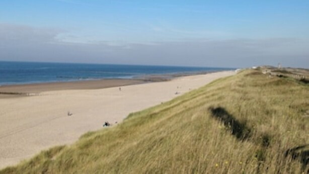 A beach with a grassy hill in the foreground and a clear sky. - Comfortable apartment in a cozy farmhouse for 2-3 persons 22KW Wallbox (Gapinge)