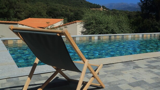 A poolside area with a wooden chair and a tiled pool. - Between sea and mountains, find peace and quiet in one of our villas (Valle-di-Mezzana)